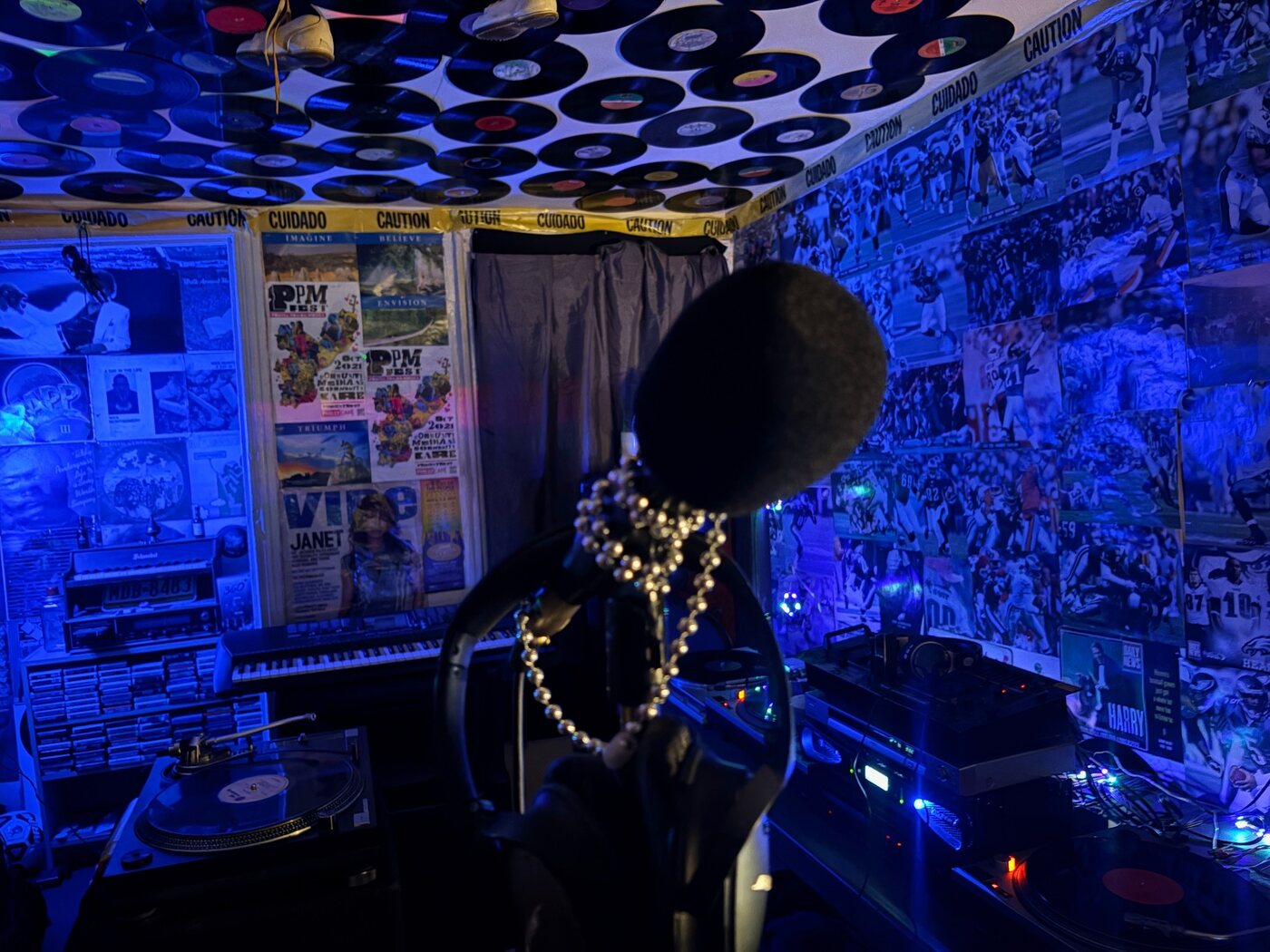Blue-lit music room filled with records, turntables, and a central figure