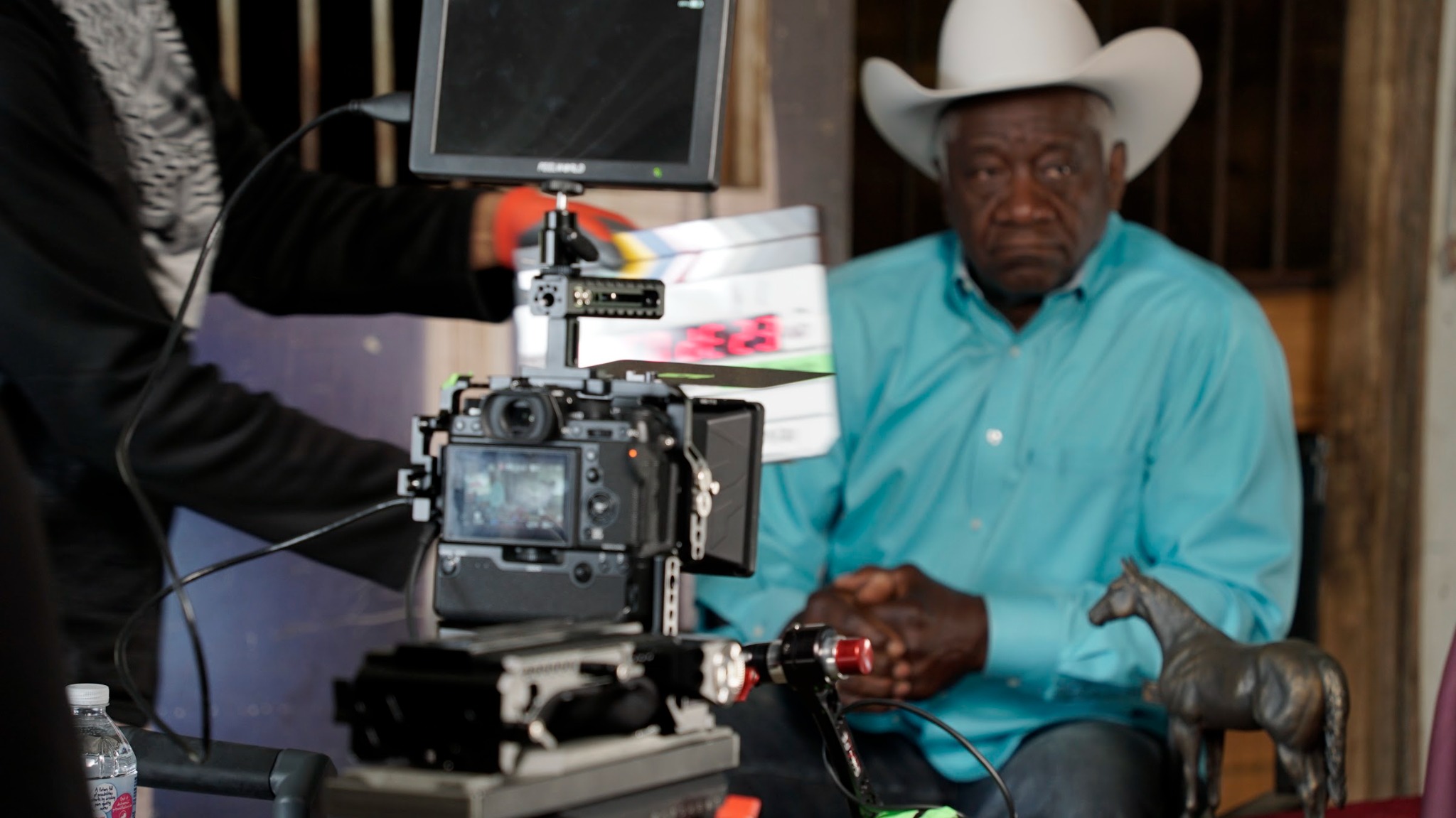 A cinema camera and production slate in front of Bob Sneed