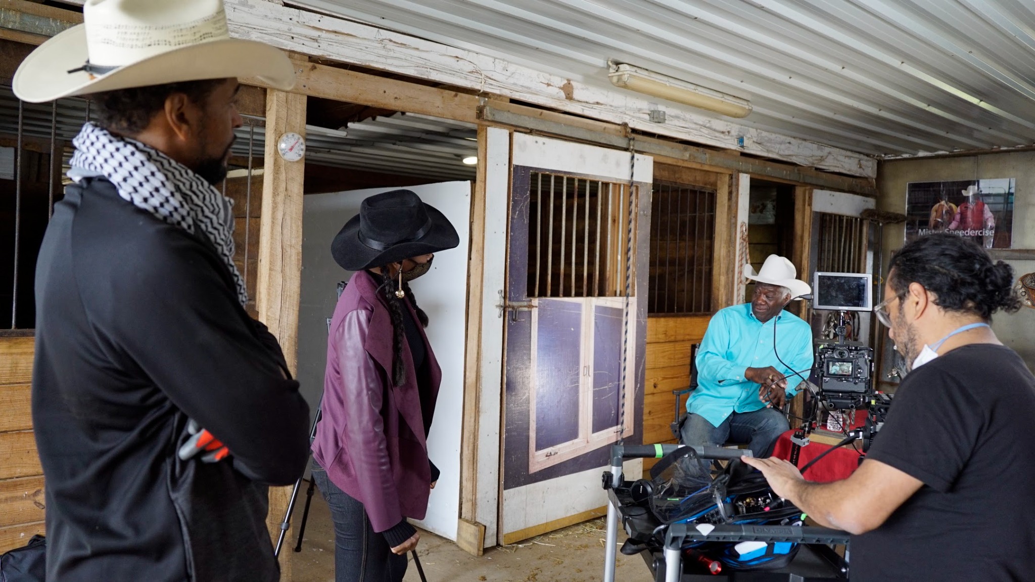 Bob Sneed seated for an interview while the Black Horsemen crew films inside the stable