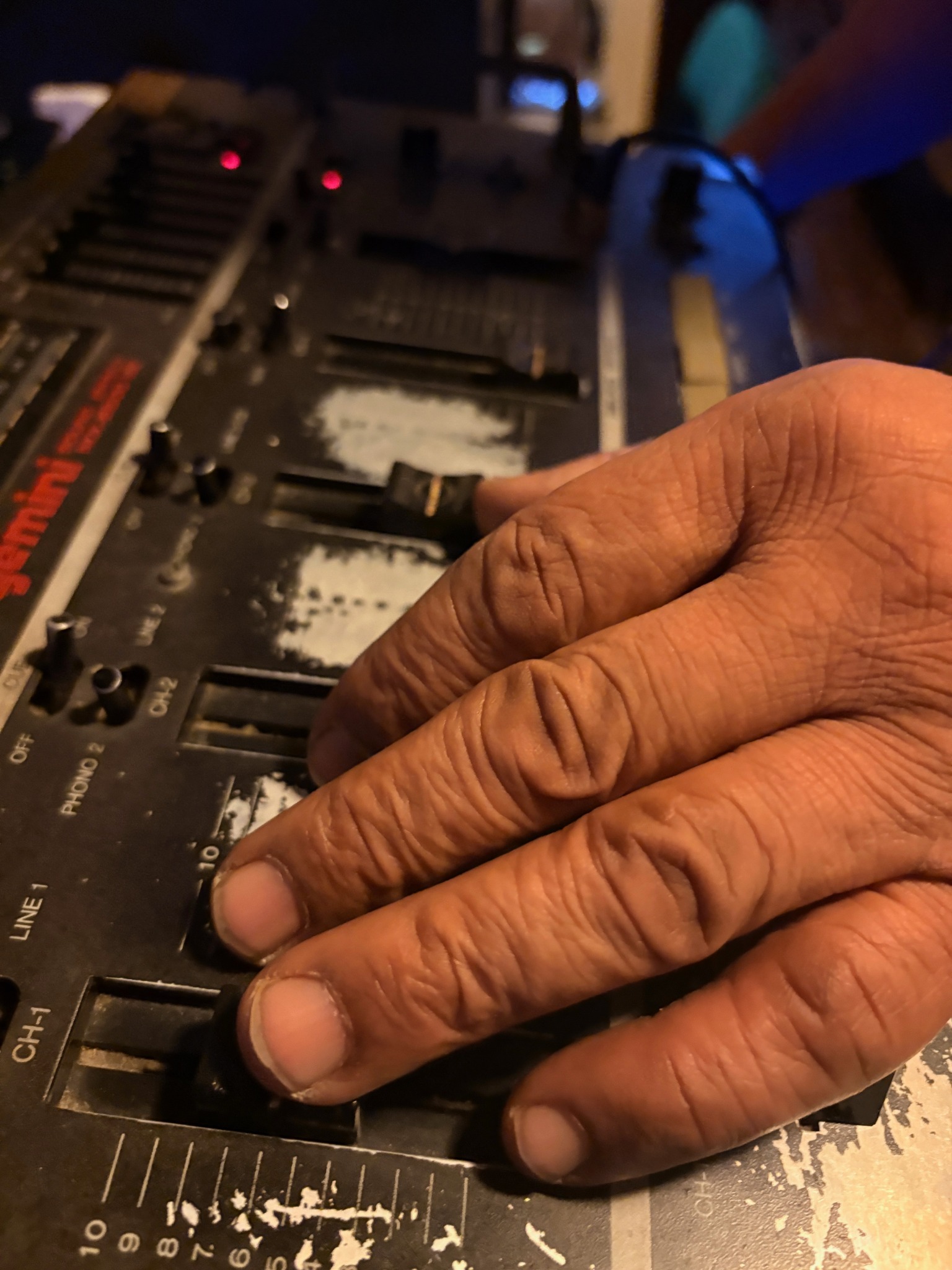 A hand working the controls of a worn audio mixer